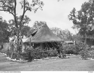 FOUR MILE VALLEY, NEW GUINEA, 1944-02-03. VX48007 CORPORAL W. INGLIS, STANDS OUTSIDE THE SALVATION ARMY HEADQUARTERS FOR THE SOUTH WEST PACIFIC AREA. THE TENT COMPRISES THE OFFICE AND STAFF LIVING ..