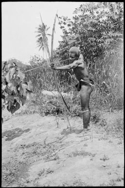 Side view of Manau, the Chinnery's house boy, firing a bow and arrow, Rabaul, New Guinea, ca. 1935 / Sarah Chinnery