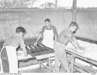 YALU, NEW GUINEA. 1945-08-03. CORPORAL J. SCRIMGEOUR (3), TINNING DOUGH IN THE BAKING WING OF THE NEW GUINEA TRAINING SCHOOL. IDENTIFIED PERSONNEL ARE:- SIGNALMAN T.O. MCMANAMNEY (1), SERGEANT ..