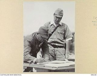 CAPE WOM, NEW GUINEA, 1945-09-13. LIEUTENANT-GENERAL ADACHI, COMMANDER 18 JAPANESE ARMY IN NEW GUINEA, SIGNING THE INSTRUMENT OF SURRENDER. HE ACCEPTED THE TERMS UNCONDITIONALLY. LIEUTENANT-GENERAL ..