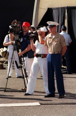 Photographer's Mate 2nd Class Dan Smith, center, and another cameraman videotape the audience at the USS ARIZONA Memorial Visitors Center during Survivor's Day ceremonies honoring the sailors and Marines of the battleships that were sunk or damaged in the Dec. 7, 1941, attack on Pearl Harbor