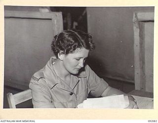 LAE, NEW GUINEA, 1945-05-21. PRIVATE P. CURRIN, AUSTRALIAN WOMEN'S ARMY SERVICE (1), CHECKING ACCOUNTS AT THE AUSTRALIAN ARMY CANTEENS SERVICE, CANTEEN BULK STORE ON BUSU ROAD