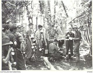 WEBER POINT, NEW GUINEA, 1944-02-14. 13248 MR. A.F. SCOTT (1), THE YOUNG MENS' CHRISTIAN ASSOCIATION WELFARE OFFICER PICTURED WITH MEMBERS OF THE 30TH INFANTRY BATTALION. HE HAS FOLLOWED THE UNIT ..