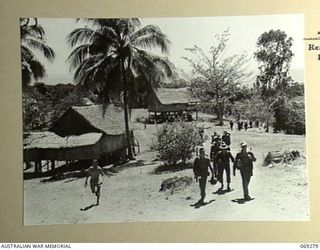 MENDAROPU, NEW GUINEA. 1942-11. INFANTRYMEN OF THE 128TH REGIMENT, 32ND UNITED STATES DIVISION MOVING ALONG THE TRACK PAST A FORMER MISSION STATION ON THE GRASSY HEIGHTS OVERLOOKING DYKE ACLAND BAY