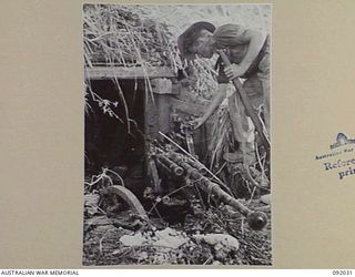 WIRUI MISSION, WEWAK AREA, NEW GUINEA, 1945-05-15. PRIVATE J.A. DONNELLY, 2/4 INFANTRY BATTALION INSPECTING A 20 MILLIMETRE GUN. IT IS ONE OF A VARIETY OF WEAPONS USED BY JAPANESE FORCES FROM ..