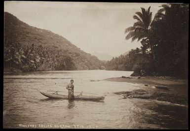 [Samoan man standing in front of a canoe in a river]