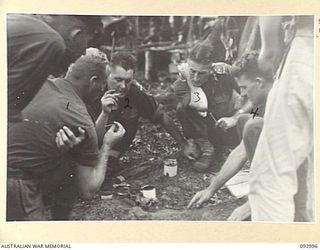 WEWAK AREA, NEW GUINEA, 1945-06-09. LT-COL W.S. HOWDEN, COMMANDING OFFICER, 2/8 INFANTRY BATTALION (3), DISCUSSING FUTURE OPERATIONS WITH SOME OF HIS OFFICERS AT A FORWARD COMPANY POSITION. ..