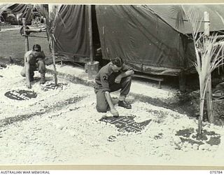 SIAR-NAGADA, NEW GUINEA. 1944-09-08. Q130661 LANCE-CORPORAL S.A. HERRIGAN (1) AND SX39026 PRIVATE J. HENNIGAN (2) WEEDING THE DECORATIVE ROCK GARDENS IN THE LINES OF A COMPANY, 61ST INFANTRY ..