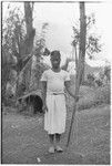 Adolescent boy stands with bow and arrows, talcum powder on face, feather valuables in hair