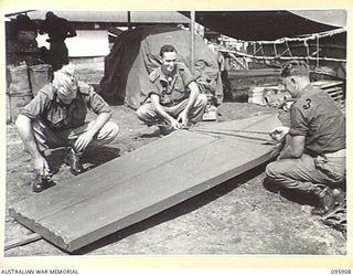 WEWAK POINT, NEW GUINEA. 1945-08-29. DRIVER H.C. WADDELL (1), SIGNALMAN E.M. NEAGLE (2) AND DRIVER E. COWARD (3), MEMBERS OF 19 INFANTRY BRIGADE, PUTTING THE FINISHING TOUCHES TO THEIR SURF BOARD. ..