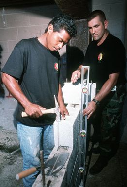 A Chuukese apprentice, Farkos Kosam, practices masonry work under the guidance of TECH. SGT. John Stainer, a structures technician from Pope Air Force Base, N.C. SGT. Stainer is a member of a thirteen man civic-action team, on 8-months temporary duty, and chartered to enhance the socio-economic development of Chuuk, while providing a U.S. military presence at this island 632 miles southeast of Guam. Exact Date Shot Unknown . Published in AIRMAN Magazine August 1997