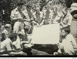 KIRIWINA, TROBRIAND ISLANDS, PAPUA. C. 1943-11. CREWS OF NO. 22 (BOSTON) SQUADRON RAAF, BEING BRIEFED. LEFT TO RIGHT: FLIGHT SERGEANT (FLT SGT) J. GRONOW; FLT SGT H. OLIVER; FLT SGT A. GIFFORD; ..