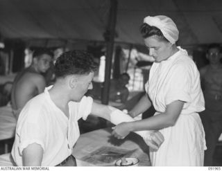 BOUGAINVILLE, 1945-04-18. PRIVATE J. WOOD (1), A SKIN PATIENT AT THE 2/1 GENERAL HOSPITAL, HAS A DRESSING APPLIED BY SISTER H. BAKER, AUSTRALIAN ARMY NURSING SERVICE (2)