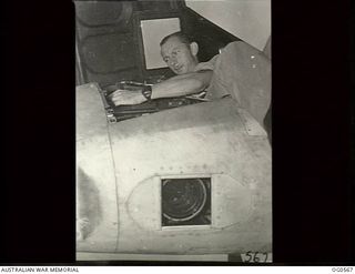 MILNE BAY, PAPUA. 1943-07-31. LEADING AIRCRAFTMAN H. HARDIE, KOGARAH, NSW, FITTING A MAGAZINE ON THE CAMERA LENS WHICH CAN BE SEEN IN THE SQUARE WINDOW IN THE NOSE OF A P38 LOCKHEED LIGHTNING ..