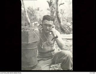 AITAPE, NORTH EAST NEW GUINEA. C. 1944-06. PILOT OFFICER G. R. GOLD, ARTARMON, NSW, ADJUTANT OF NO. 13 SURVEY AND DESIGN UNIT RAAF, USING A FIELD TELEPHONE CAPTURED FROM THE JAPANESE IN THE AITAPE ..