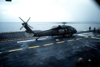 An Army UH-60 Black Hawk helicopter on the flight deck of the amphibious assault ship USS GUAM (LPH 9) during Operation URGENT FURY