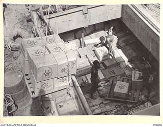 LAE AREA, NEW GUINEA, 1945-07-11. NATIVES IN THE HOLD OF A SHIP POSITIONING HAMPERS FOR SHIPMENT TO OPEN BAY, NEW BRITAIN. THEY ARE MID-YEAR HAMPERS FOR DISTRIBUTION BY THE AUSTRALIAN COMFORTS ..