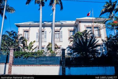 New Caledonia - two storey colonial building behind fence, flying French flag