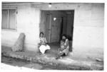 Group portrait, two women seated at front door