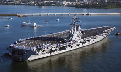An aerial starboard stern view of the US Navy (USN) Nimitz Class Aircraft Carrier, USS RONALD REAGAN (CVN 76) showing her crew manning the rails and rendering honors as it sails past the Battleship USS Arizona (BB 39) Memorial upon her maiden port visit to Pearl Harbor, Hawaii (HI), as she heads to the Indian Ocean to participate in Operation UNIFIED ASSISTANCE, the humanitarian relief effort in response to the tsunami that devastated Southeast Asia on December 26, 2004