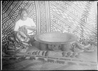 Man sitting on a woven mat beside a large bowl, Fiji, ca. 1920 / E.W. Searle