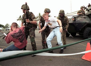 Marines of 11th Marine Expeditionary Unit (MEU) Camp Pendleton, CA, armed with 5.56mm M16A2 assault rifles, assist two civilians to their feet during a simulated Noncombatant Evacuation Operation (NEO) at Kaneohe Bay Marine Corps Station, HI. During Operation RIMPAC 96 Marines conducted training exercises in the evacuation of civilians from hostile foreign environments