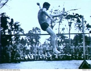 THE SOLOMON ISLANDS, 1945-01-12. A COMPETITOR CLEARS THE BAR DURING THE HIGH JUMP AT A COMBINED ANZAC SPORTS MEETING AT BOUGAINVILLE ISLAND. (RNZAF OFFICIAL PHOTOGRAPH.)