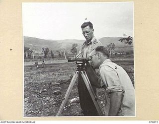 WAU, NEW GUINEA. 1944-02-23. SX18491 LIEUTENANT R S GERNY (1), WITH VX72524 SAPPER N RITCHIE (2), MEMBERS OF THE 2/4TH FIELD SQUADRON, CHECKING LEVELS PRIOR TO CONSTRUCTION OF THE REST CAMP AT WAU