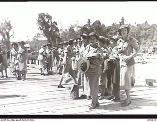 MILFORD HAVEN, NEW GUINEA, 1945-12-14. MEMBERS OF THE AUSTRALIAN ARMY NURSING SERVICE AND THE AUSTRALIAN ARMY MEDICAL WOMEN'S SERVICE WAITING THEIR TURN TO EMBARK ABOARD THE AUSTRALIAN TROOPSHIP SS ..