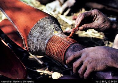 Red ochre is used to highlight the carved patterns on this drum using a pandanus-nut brush