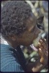 Western Highlands: woman with facial tattoo, eating yam