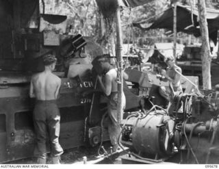 BOUGAINVILLE. 1945-08-30. MEMBERS OF 2/4 ARMOURED REGIMENT WORKSHOP WELDING AND FITTING A BULLDOZER BLADE ON TO A MATILDA TANK. THE PORTABLE WELDING PLANT IS INSTALLED IN REAR OF JEEP