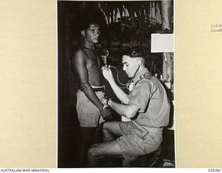 NEW GUINEA. 1942-08. A FUZZY HAIRED PAPUAN EXAMINED BY CAPTAIN P. JENSEN, COMMANDING OFFICER OF NATIVE MEDICAL SERVICES