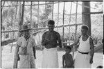 Men, one smoking a pipe, under a building frame