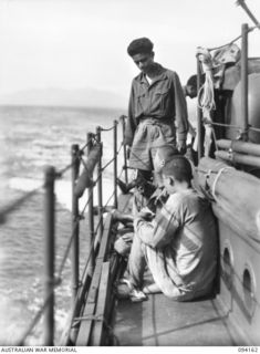 TINIAN, BOUGAINVILLE. 1945-07-18. PRIVATE J. PATTY, NETHERLANDS EAST INDIES ARMY, STANDS BY JAPANESE PRISONERS OF WAR ON THE DECK OF THE MOTOR LAUNCH ML1327 WATCHING THEM EAT. THE VESSEL IS BEING ..