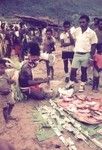 Pearlshells (smeared with red pigment) and Australian currency are prepared for ceremonial exchange, as a mission convert looks on