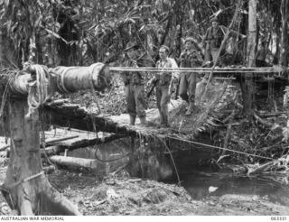 FAITA, RAMU VALLEY, NEW GUINEA. 1944-01-07. MEMBERS OF THE 2/2ND COMMANDO SQUADRON CROSSING A SWING BRIDGE IN THE UNIT HEADQUARTERS AREA. PICTURED HERE ARE: SERGEANT A. DIXON OF SUMMERHIL, NSW, PAY ..