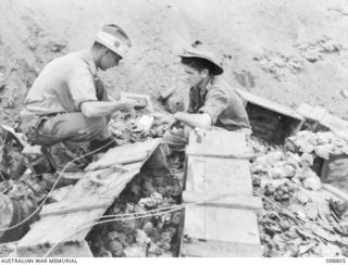 VULCAN, RABAUL AREA, NEW BRITAIN. 1945-11-14. LIEUTENANT J. MUNRO, AND HIS SERGEANT, MEMBERS OF HEADQUARTERS 11 DIVISION, SET THE FUSE FOR THE DESTRUCTION OF APPROXIMATELY 20 TONS OF JAPANESE ..