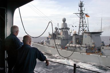 US Navy (USN) Sailors stationed onboard the Tarawa Class Amphibious Assault Ship, USS SAIPAN (LHA 2), observe as Replenishment At Sea (RAS) operations are conducted with the German Navy, Bremen Class (Type 122) Frigate, FGS NIEDERSACHSEN (F 208), while the ships are underway in the Atlantic Ocean participating in the North Atlantic Treaty Organization (NATO) Standing Naval Force Atlantic (SNFL) 2004. The Standing Naval Force is a squadron of eight to ten destroyers and frigates from different nations in the NATO organization