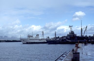 A view of part of the U.S. Navy Bishop Point facility showing the salvage ship USS SALVOR (ARS-52) and the ocean surveillance ship USNS ASSURANCE (T-AGOS-5) tied up at the piers