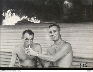 VIVIGANI, GOODENOUGH ISLAND, PAPUA. C. 1943-10. SMOKING IN THE PARACHUTE SECTION IS STRICTLY FORBIDDEN SO LEADING AIRCRAFTMAN (LAC) A. N. BELCHER, BLACKWOOD, SA (RIGHT) GIVES A LIGHT TO A CIGARETTE ..