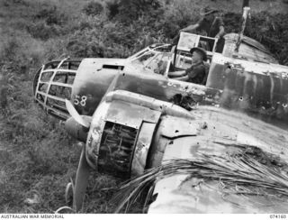 HANSA BAY, NEW GUINEA. 1944-06-19. QX48006 SAPPER D. MCSTAY (1) AND NX155299 SAPPER L.H. KENT (2) BOTH OF HEADQUARTERS, 5TH DIVISION, INSPECTING A BADLY DAMAGED JAPANESE TWIN ENGINED BOMBER ..