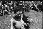 Bomagai: woman with face and body smeared with clay as a sign of mourning, she holds infant