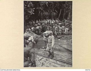 KAIRIRU ISLAND, NEW GUINEA. 1945-09-17. JAPANESE NAVAL PERSONNEL MOVING ONTO BARGE FOR TRANSFER TO MUSCHU ISLAND. THEIR GEAR HAS BEEN SEARCHED BY SECURITY PERSONNEL. FOLLOWING THE SURRENDER OF THE ..
