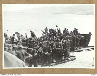 KANOMI BEACH, NEW GUINEA. 1944-01-05. TROOPS OF THE 2/23RD AUSTRALIAN INFANTRY BATTALION, 26TH AUSTRALIAN INFANTRY BRIGADE, 9TH AUSTRALIAN DIVISION BOARDING BARGES WHICH ARE TO TAKE THEM UP THE ..