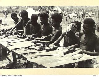 RAMU VALLEY, NEW GUINEA. 1944-02-04. NATIVES SCRUBBING WEBBING EQUIPMENT SALVAGED FROM FORWARD AREAS BY THE ORDNANCE SERVICE, 7TH DIVISION