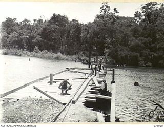 "COOGEE BEACH", JACQUINOT BAY, NEW BRITAIN. 1945-02-01. SAPPERS OF THE 4TH FIELD COMPANY, BUILDING A PERMANENT BRIDGE OVER THE TAUT RIVER TO CONNECT THE 5TH DIVISION AREA WITH THE WUNUNG PLANTATION