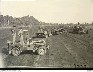 BUT, NORTHERN NEW GUINEA. 1945-04-02. FLYING OFFICER J. C. RUSH OF EARLWOOD, NSW, WITH AN AUSTRALIAN ARMY COLONEL STANDING IN A JEEP, SERIAL NO. 58091, MAKING AN INSPECTION OF THE BUT AUSTER AIR ..