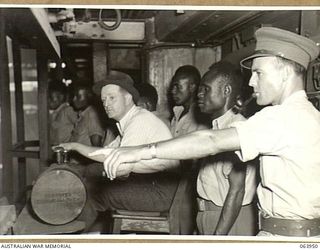 NEWCASTLE, NSW. 1944-01-28. AUSTRALIAN AND NEW GUINEA ADMINISTRATION UNIT NATIVES WATCHING STEEL PLATE BEING ROLLED AT THE MILLS OF THE BROKEN HILL PTY