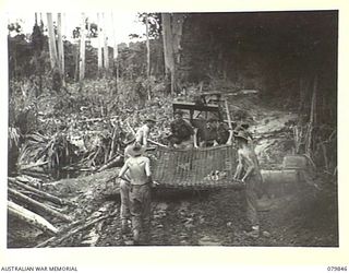 MEVELO RIVER, NEW BRITAIN. 1945-03-15. MEMBERS OF THE 4TH FIELD COMPANY, ROYAL AUSTRALIAN ENGINEERS LOAD WIRE MESH ON TO A SLEDGE TOWED BY TRACTOR BETWEEN MEVELO AND HENRY REID RIVERS